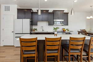 Kitchen with pendant lighting, a center island, a breakfast bar, and sink