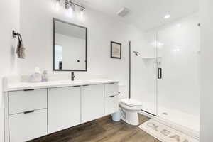 Master Bathroom with a shower with shower door, vanity, toilet, and hardwood / wood-style floors