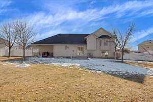 Snow covered back of property with a yard