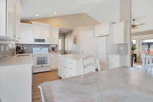 Kitchen with white cabinetry, sink, white appliances, and tasteful backsplash