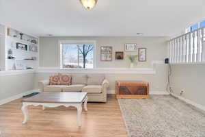 Living room with built in shelves and light hardwood / wood-style flooring