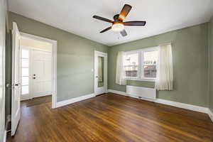 Empty room featuring radiator, ceiling fan, and dark wood-type flooring