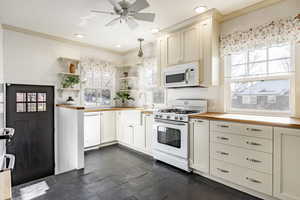 Kitchen featuring butcher block counters, ceiling fan, white appliances, pendant lighting, and sink