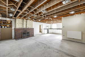 Basement featuring a brick fireplace, radiator heating unit, and wine cooler