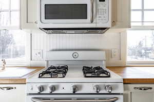 Kitchen with white cabinetry, white appliances, and a healthy amount of sunlight