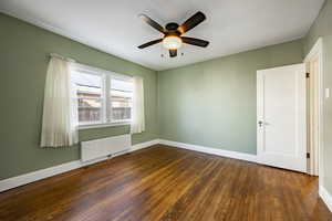 Spare room featuring radiator, dark wood-type flooring, and ceiling fan