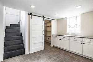 Basement with a barn door, a textured ceiling, and carpet flooring