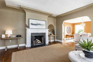 Living room featuring dark hardwood / wood-style flooring, crown molding, and a notable chandelier