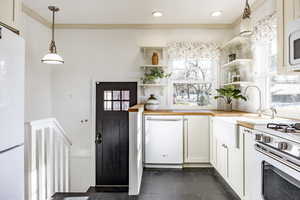 Kitchen featuring pendant lighting, butcher block countertops, sink, white appliances, and white cabinetry