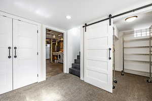 Basement featuring a barn door, independent washer and dryer, and a textured ceiling