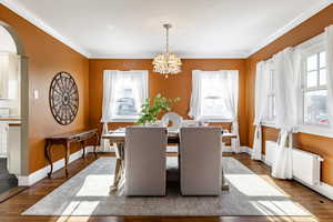 Dining space featuring a healthy amount of sunlight, wood-type flooring, and a chandelier