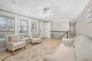 Tiled living room featuring ceiling fan and ornamental molding