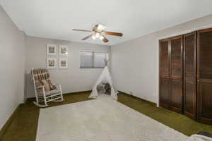 Bedroom featuring ceiling fan, a closet, and dark colored carpet