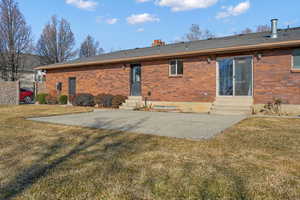 Rear view of house with a lawn and a patio