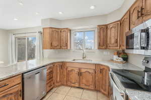 Kitchen with a wealth of natural light, appliances with stainless steel finishes, sink, and light tile patterned floors