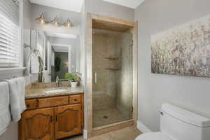 Bathroom with toilet, tile patterned flooring, an enclosed shower, and vanity