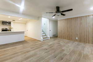 Unfurnished living room featuring ceiling fan and light hardwood / wood-style flooring