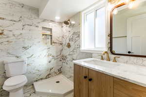 Bathroom featuring a textured ceiling, toilet, walk in shower, and vanity