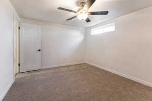 Empty room with ceiling fan, carpet, and a textured ceiling