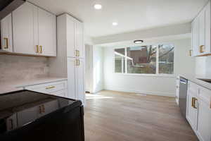 Kitchen featuring white cabinetry, light hardwood / wood-style floors, decorative backsplash, black electric range, and stainless steel dishwasher