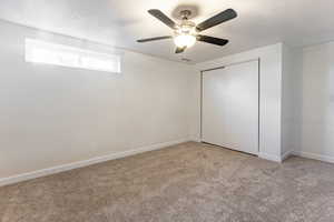 Unfurnished bedroom featuring ceiling fan, a textured ceiling, a closet, and light carpet