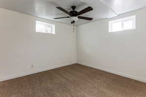 Carpeted empty room with ceiling fan, a wealth of natural light, and a textured ceiling