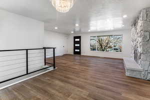 Foyer with a textured ceiling, a fireplace, dark hardwood / wood-style floors, and a notable chandelier