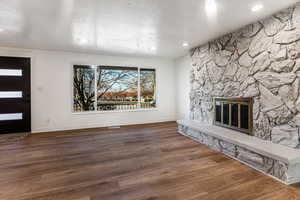 Unfurnished living room with a textured ceiling, a fireplace, and dark hardwood / wood-style floors