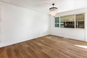 Empty room with a chandelier and hardwood / wood-style floors