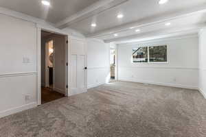 Carpeted spare room featuring beamed ceiling