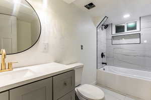 Full bathroom featuring tiled shower / bath combo, vanity, and toilet