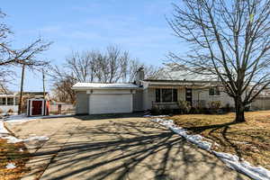 Ranch-style house featuring a garage, a porch, and a storage shed