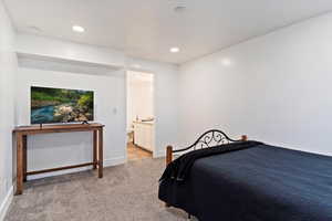 Bedroom with ensuite bathroom and light colored carpet