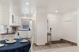 Kitchen with decorative backsplash, dishwasher, white cabinets, and electric stove