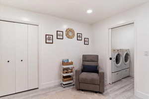 Clothes washing area with separate washer and dryer and light hardwood / wood-style flooring