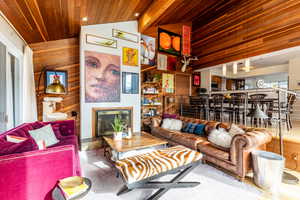 Living room with wooden walls, wooden ceiling, and lofted ceiling with beams