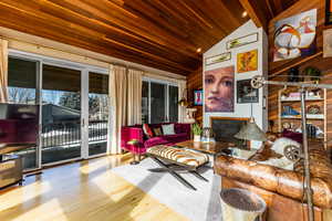 Living room with wood ceiling, light hardwood / wood-style flooring, vaulted ceiling with beams, and wood walls