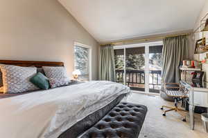 Carpeted bedroom featuring lofted ceiling and access to outside