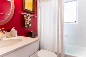 Full bathroom with shower / bath combination with curtain, vanity, and toilet