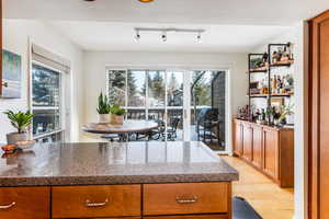 Kitchen with light hardwood / wood-style floors, dark stone countertops, and a healthy amount of sunlight