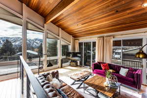 Sunroom / solarium with beam ceiling, plenty of natural light, wood ceiling, and a mountain view