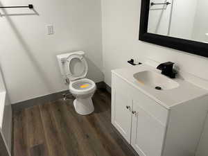 Bathroom with toilet, hardwood / wood-style floors, and vanity