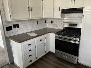 Kitchen featuring tasteful backsplash, dark hardwood / wood-style floors, stainless steel range with gas stovetop, and white cabinetry