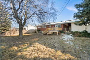 Rear view of house with a lawn and a deck