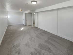 Basement featuring a textured ceiling and carpet flooring