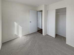 Unfurnished bedroom featuring light colored carpet and a closet