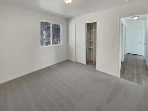 Unfurnished bedroom featuring a textured ceiling and light carpet