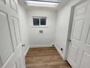 Laundry area with light wood-type flooring, washer hookup, and hookup for an electric dryer