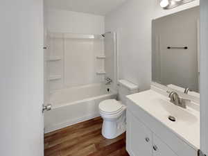 Full bathroom featuring washtub / shower combination, toilet, hardwood / wood-style flooring, and vanity