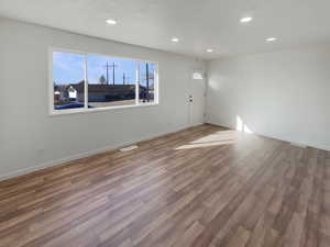 Unfurnished room featuring hardwood / wood-style flooring and a textured ceiling